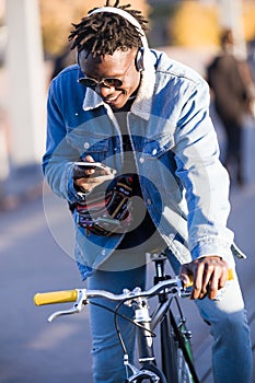 Handsome young man using mobile phone and fixed gear bicycle in the street.