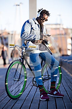 Handsome young man using mobile phone and fixed gear bicycle in the street.