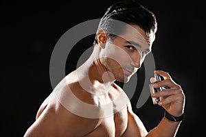 Handsome young man using perfume on background