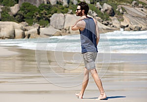 Handsome young man walking alone on empty beach