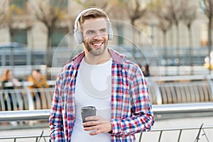 Handsome young man wear headphones and smiling while listening music and drinking coffee, morning inspiration.