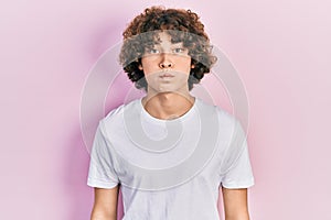 Handsome young man wearing casual white t shirt puffing cheeks with funny face