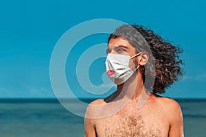 Handsome young man wearing face mask and medical gloves outdoors portrait on the beach