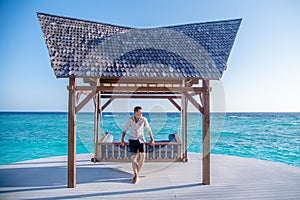 Handsome young man wearing fashionable shirt walking near standing meat swing at the tropical island luxury resort