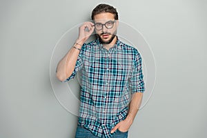 handsome young man wearing plaid shirt and adjusting eyeglasses