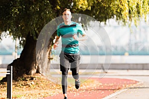 Handsome young man wearing sportswear and running at quay during
