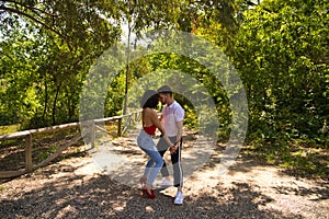 Handsome young man and woman dancing bachata and salsa in the park. The couple dance passionately surrounded by greenery. Dancing