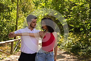 Handsome young man and woman dancing bachata and salsa in the park. The couple dance passionately surrounded by greenery. Dancing