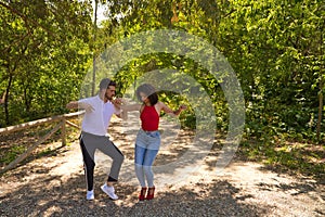 Handsome young man and woman dancing bachata and salsa in the park. The couple dance passionately surrounded by greenery. Dancing