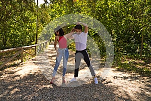 Handsome young man and woman dancing bachata and salsa in the park. The couple dance passionately surrounded by greenery. Dancing