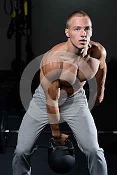 Handsome young man working out in gym kettlebell