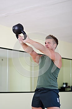 Handsome young man working out in gym with kettlebell