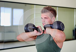 Handsome young man working out in gym with kettlebells photo