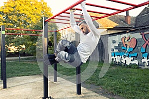 Handsome young man working out his abs while hanging on the horizontal ladder, side abs