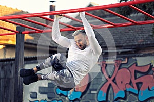 Handsome young man working out his abs while hanging on the horizontal ladder, side abs