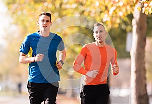 Handsome young men wearing sportswear and running at quay during