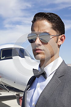 Handsome young men wearing sunglasses with private plane in background