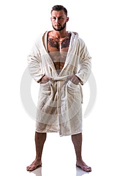 Handsome muscular young man wearing white bathrobe, isolated