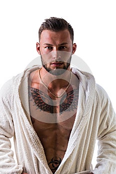 Handsome muscular young man wearing white bathrobe, isolated