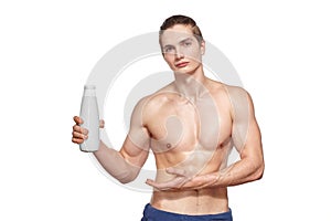 Handsome young muscular athlete holding bottle of