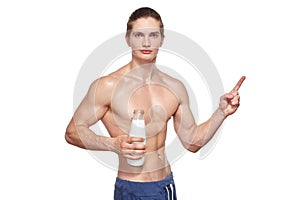 Handsome young muscular athlete holding bottle of