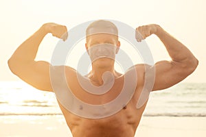 Handsome young muscular male model doing the workout stretching warm up on the beach summer.sexy athlete abs and perfect