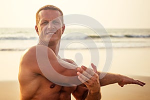 Handsome young muscular male model doing the workout stretching warm up on the beach summer.sexy athlete abs and perfect