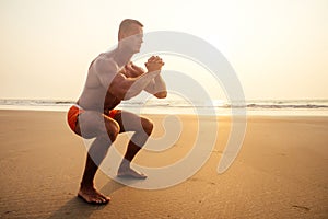 Handsome young muscular male model doing the workout stretching warm up on the beach summer.sexy athlete abs and perfect