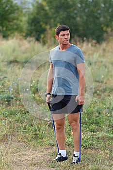 Handsome young muscular sports man exercising outside outdoor with rubber band.