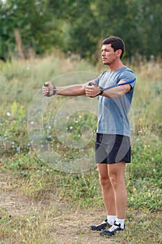 Handsome young muscular sports man exercising outside outdoor with rubber band.