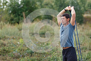 Handsome young muscular sports man exercising outside outdoor with rubber band.