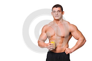 Handsome young muscular sports man holding a glass of juice isolated