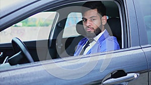Handsome young muslim man sitting in the car and looking with piercing glance.