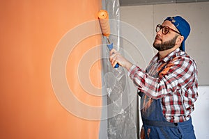 Handsome young painter man with happy smile painting the wall. Repair, building and home concept.