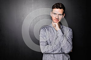 Handsome young pensive man standing and looking up isolated on the gray background