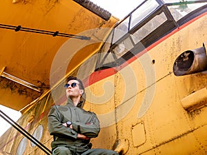 A handsome young pilot sitting on the wing of a plane