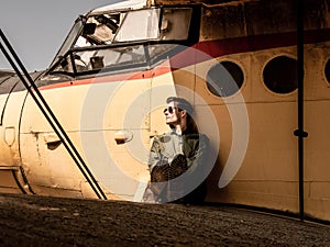 A handsome young pilot sitting on the wing of a plane