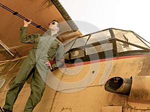 A handsome young pilot standing on the wing of a plane