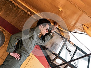 A handsome young pilot standing on the wing of a plane