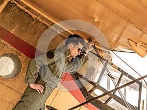 A handsome young pilot standing on the wing of a plane