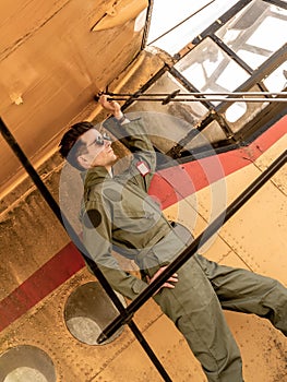 A handsome young pilot standing on the wing of a plane