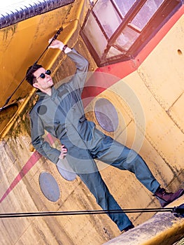 A handsome young pilot standing on the wing of a plane