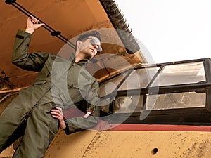 A handsome young pilot standing on the wing of a plane