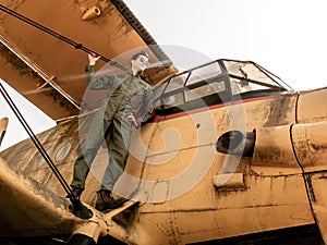 A handsome young pilot standing on the wing of a plane