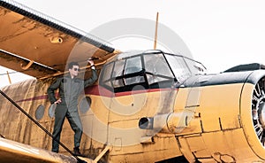 A handsome young pilot standing on the wing of a plane