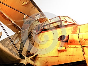 A handsome young pilot standing on the wing of a plane