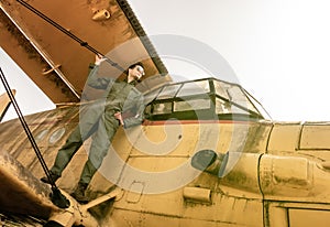 A handsome young pilot standing on the wing of a plane