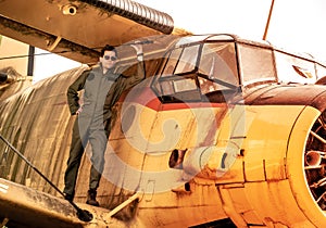 A handsome young pilot standing on the wing of a plane