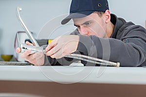 Handsome young plumber fixing tap at cleints home