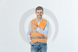 Handsome young professional engineer man over grey wall wearing orange vest amazed and surprised looking and pointing